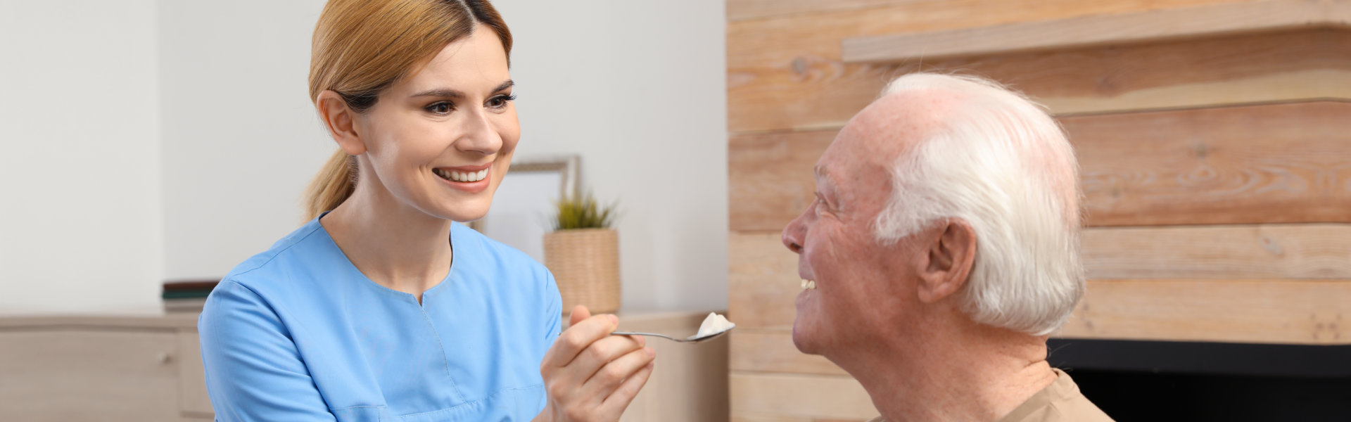 a caregiver woman feeding an elderly man
